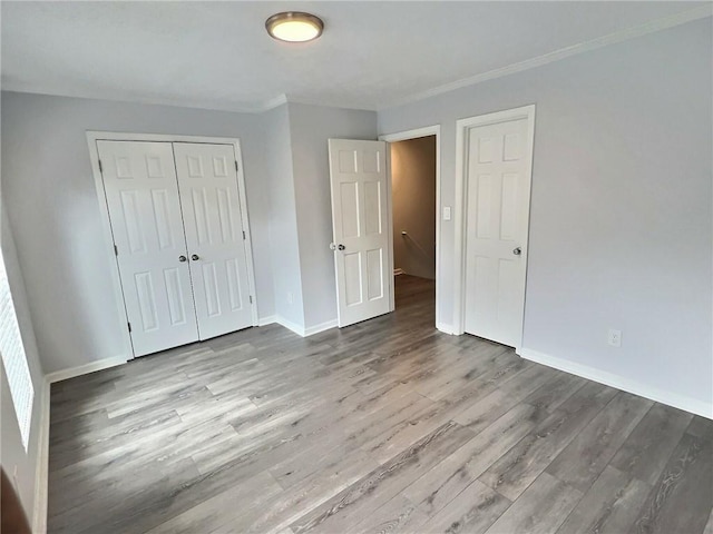 unfurnished bedroom with ornamental molding, light wood-type flooring, and a closet