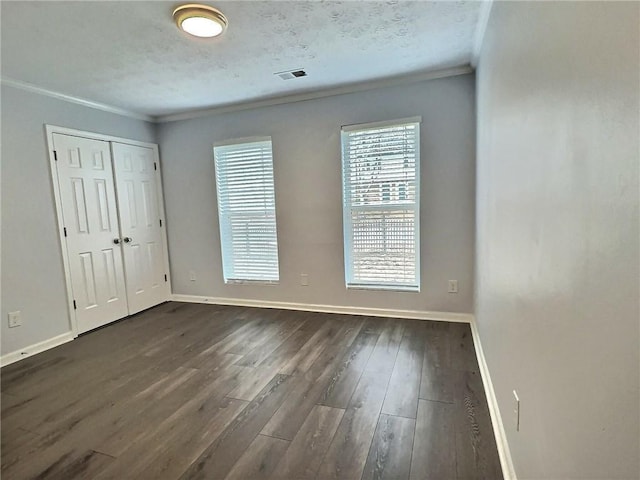 empty room featuring dark wood-type flooring, ornamental molding, and a textured ceiling