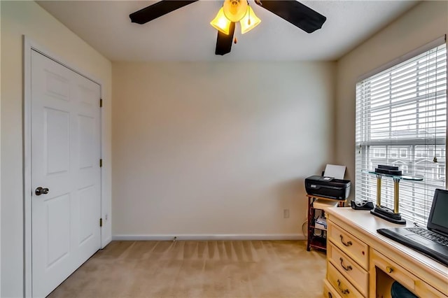 office space with a ceiling fan, light colored carpet, and baseboards