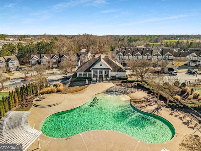 community pool with a residential view and a patio area