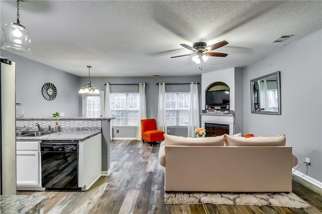 living room featuring baseboards, visible vents, ceiling fan, wood finished floors, and a fireplace