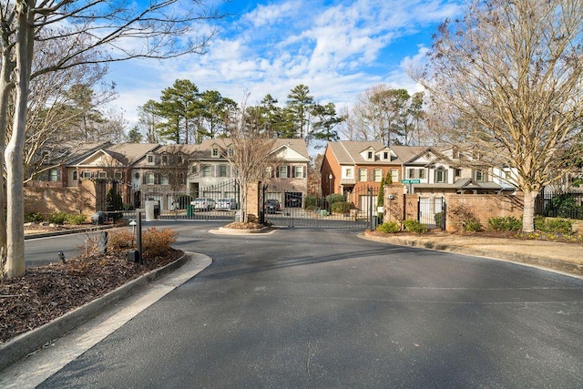 view of road featuring curbs, a gated entry, a gate, and a residential view