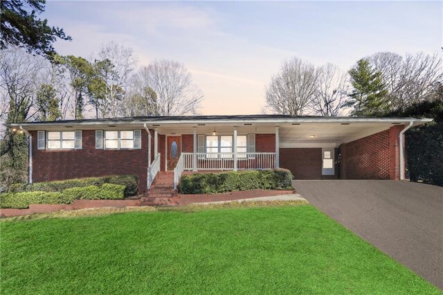 ranch-style home featuring a yard, a porch, and a carport