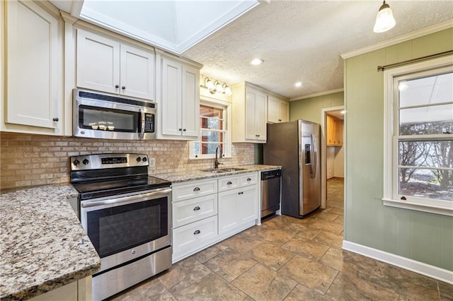 kitchen featuring sink, appliances with stainless steel finishes, a textured ceiling, ornamental molding, and light stone counters