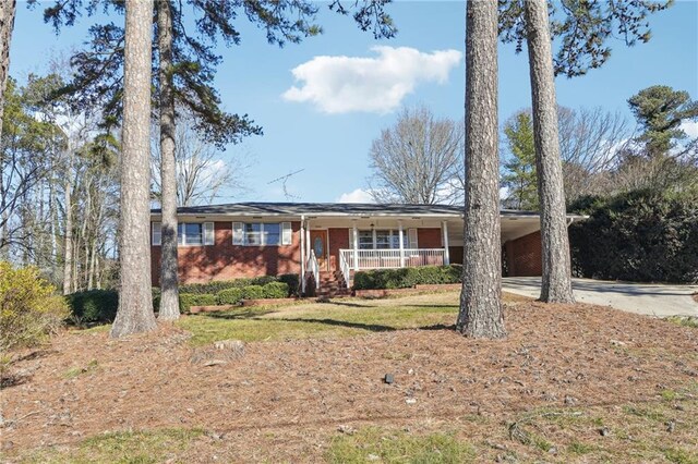 single story home featuring a front yard, a porch, and a carport