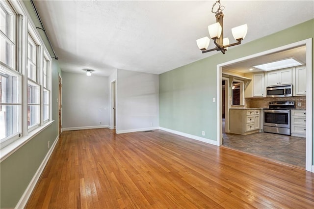 interior space featuring a skylight, a chandelier, and light hardwood / wood-style floors