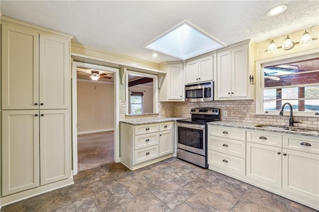 kitchen featuring a skylight, appliances with stainless steel finishes, plenty of natural light, and sink