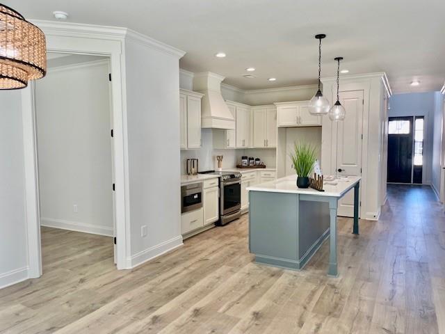 kitchen with stainless steel electric range, a breakfast bar, white cabinetry, a center island, and wall chimney exhaust hood