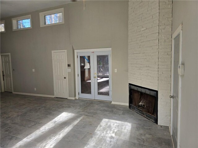 1920 Moores Mill Rd NW, Atlanta, GA 30318 - unfurnished living room featuring baseboards, a fireplace, french doors, and a towering ceiling