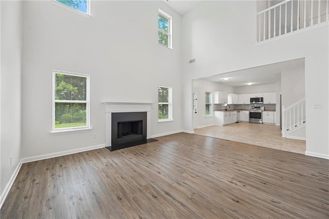 3405 Summer Brooke Way, Union City, GA 30291 - unfurnished living room featuring a towering ceiling, light wood-type flooring, a fireplace with flush hearth, and stairs