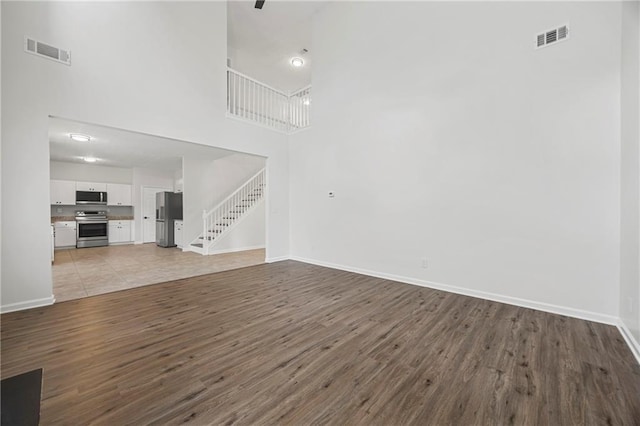 3405 Summer Brooke Way, Union City, GA 30291 - unfurnished living room featuring stairs, wood finished floors, and a towering ceiling