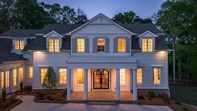 rear view of property featuring covered porch and roof with shingles