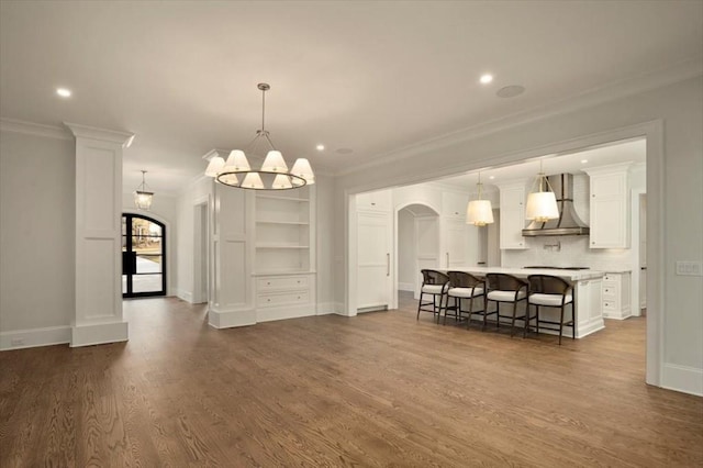 living room featuring crown molding, arched walkways, dark wood-style flooring, recessed lighting, and baseboards