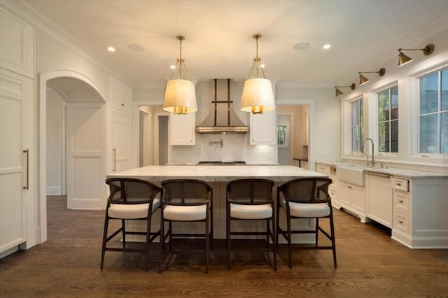 kitchen featuring wall chimney exhaust hood, a sink, white cabinetry, backsplash, and dishwasher