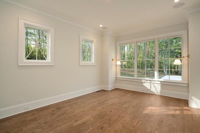 empty room featuring ornamental molding, healthy amount of natural light, baseboards, wood finished floors, and recessed lighting