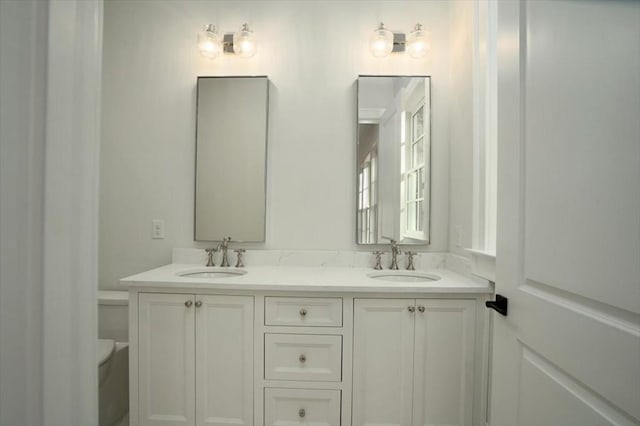 bathroom with double vanity and toilet