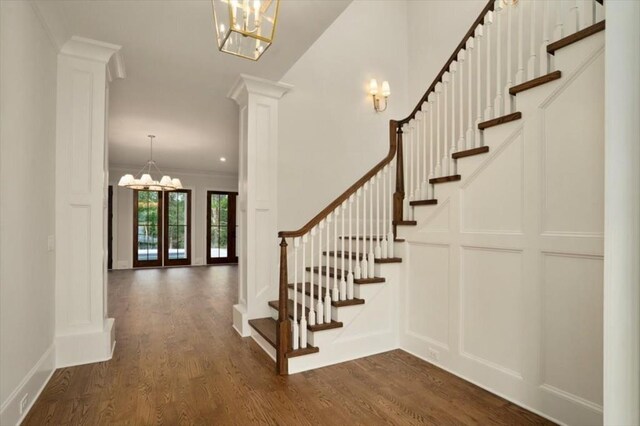 foyer entrance featuring a chandelier, stairway, dark wood finished floors, and ornamental molding