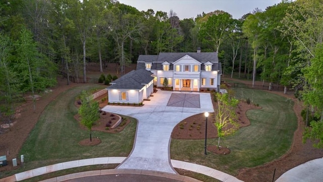view of front of house featuring curved driveway, a front lawn, and a forest view
