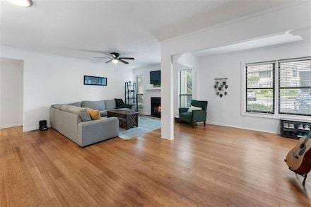 3828 Woodridge Way, Tucker, GA 30084 - living area with ceiling fan, wood finished floors, and a warm lit fireplace