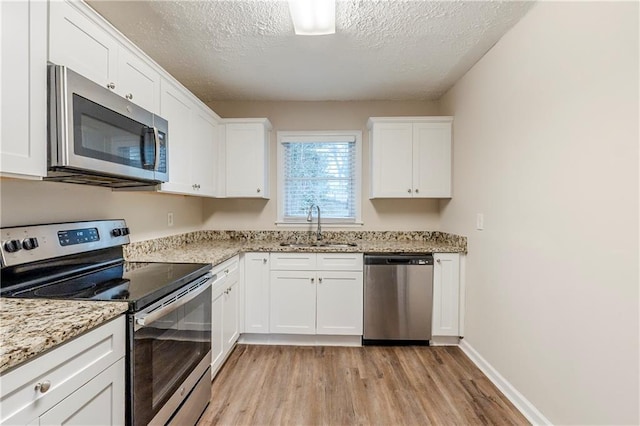 2504 Brentwood Rd, Decatur, GA 30032 - kitchen with light wood-style flooring, a textured ceiling, a sink, white cabinets, and appliances with stainless steel finishes