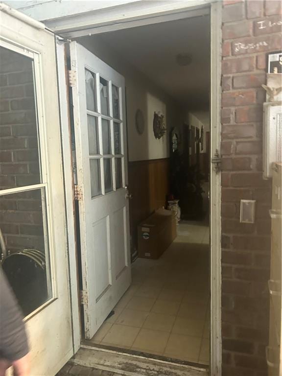 hall featuring tile patterned flooring and brick wall