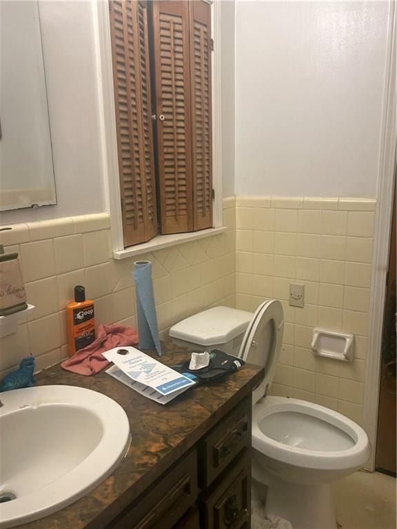 bathroom featuring vanity, tile walls, and toilet