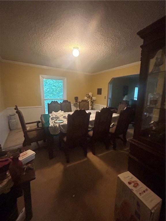 dining area with crown molding, carpet floors, and a textured ceiling