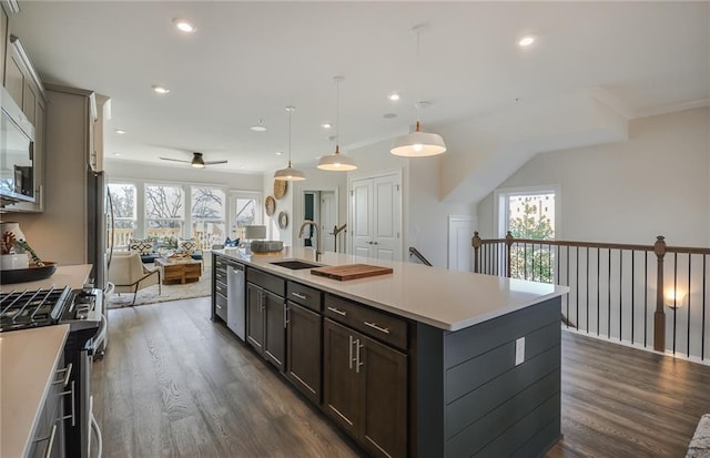 kitchen featuring stainless steel appliances, hanging light fixtures, a kitchen island with sink, and dark wood-type flooring