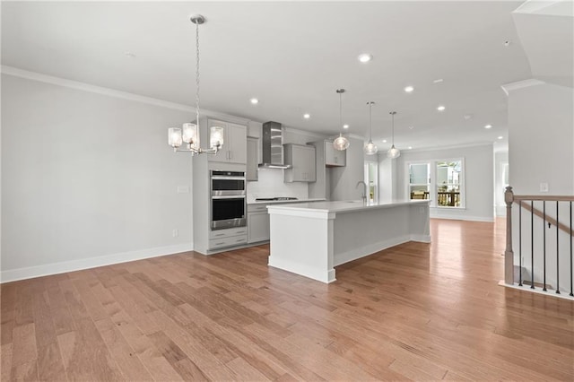 kitchen featuring gray cabinets, a spacious island, decorative light fixtures, and wall chimney exhaust hood