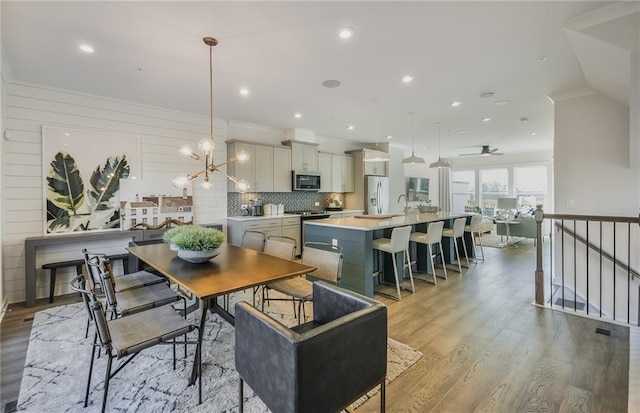 dining room with ornamental molding, an inviting chandelier, light hardwood / wood-style floors, and sink