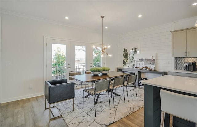 dining area with light hardwood / wood-style floors, french doors, ornamental molding, and a chandelier