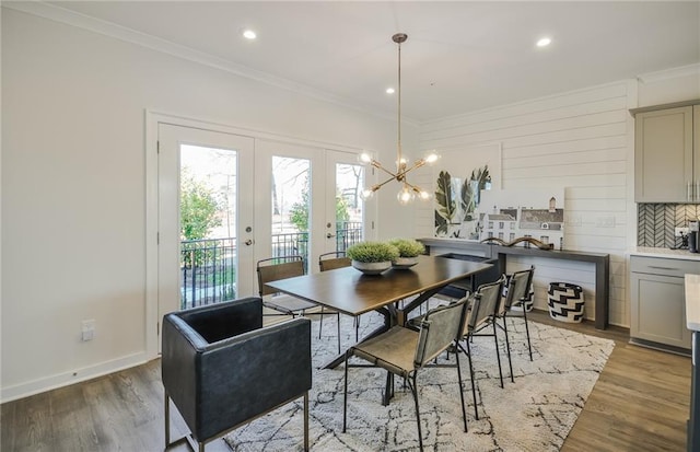 dining space with french doors, hardwood / wood-style floors, ornamental molding, and a chandelier