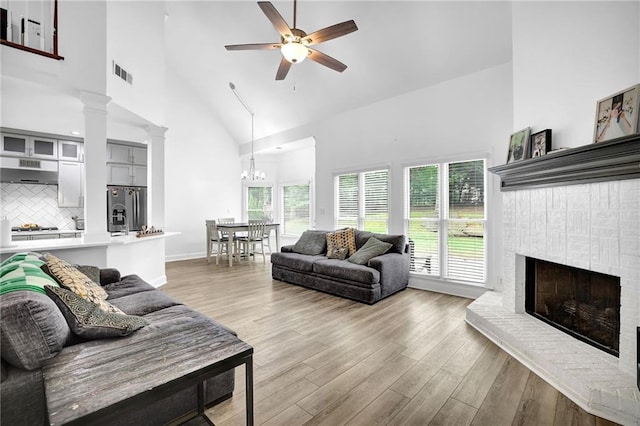 2330 Wood Creek Ct, Dacula, GA 30019 - living room with a ceiling fan, high vaulted ceiling, light wood-style floors, a fireplace, and ornate columns