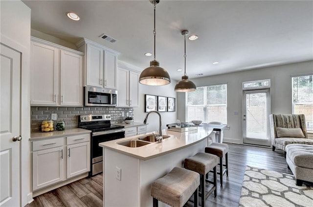 kitchen featuring stainless steel appliances, tasteful backsplash, light countertops, white cabinets, and a sink