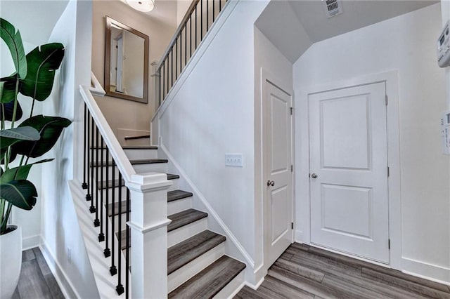 stairs featuring wood finished floors, visible vents, and baseboards