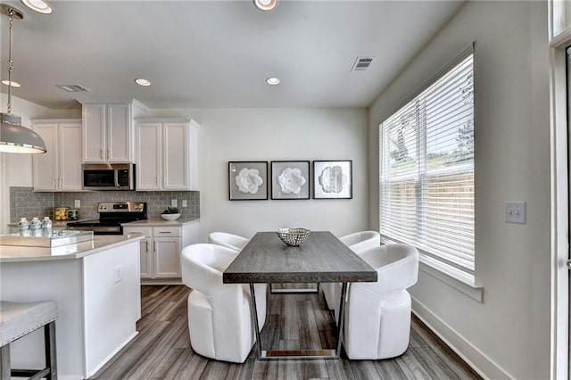 dining space with recessed lighting, wood finished floors, visible vents, and baseboards