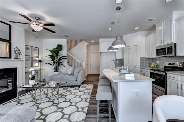 kitchen with stainless steel appliances, visible vents, open floor plan, light countertops, and tasteful backsplash