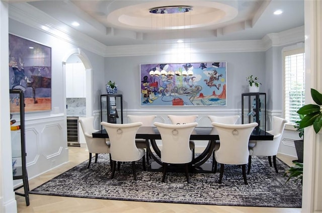 dining area with beverage cooler, ornamental molding, a raised ceiling, and a decorative wall