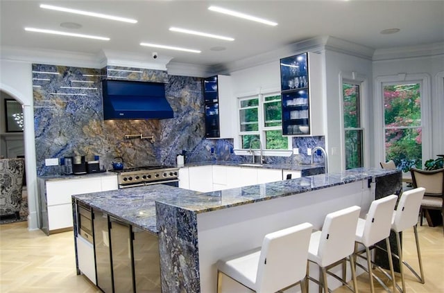 bar with custom exhaust hood, high end stainless steel range, backsplash, ornamental molding, and a sink