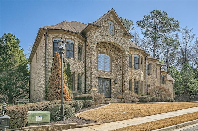 french country inspired facade featuring stone siding and brick siding