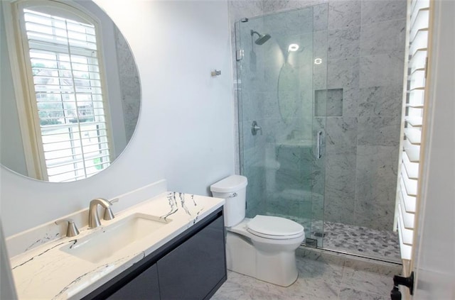 bathroom featuring marble finish floor, vanity, a shower stall, and toilet