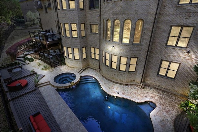 back of house featuring a pool with connected hot tub, a patio, and brick siding