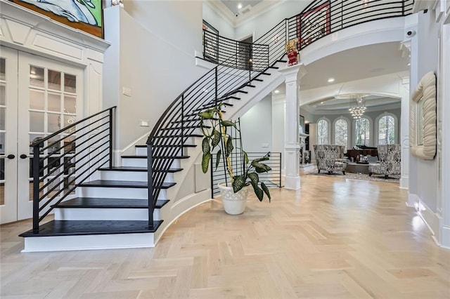 foyer featuring arched walkways, a notable chandelier, crown molding, a towering ceiling, and baseboards