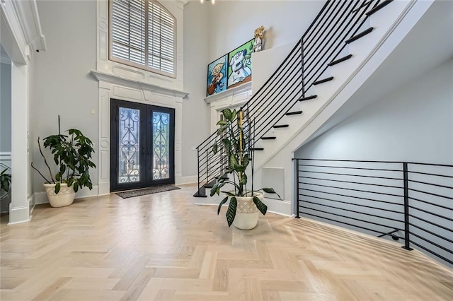 entrance foyer with stairs, a high ceiling, baseboards, and french doors