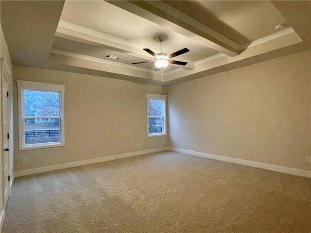 carpeted spare room featuring ceiling fan, plenty of natural light, and a tray ceiling