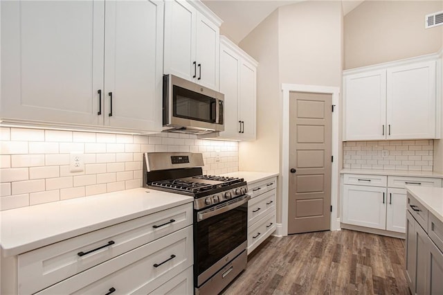 kitchen featuring white cabinetry, backsplash, hardwood / wood-style flooring, and appliances with stainless steel finishes