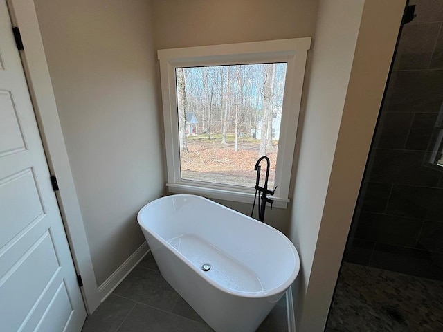 bathroom featuring tile patterned flooring, a bathtub, and plenty of natural light