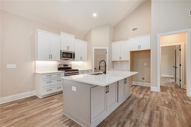 kitchen featuring sink, appliances with stainless steel finishes, an island with sink, light hardwood / wood-style floors, and white cabinets