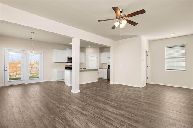 unfurnished living room featuring dark hardwood / wood-style flooring and ceiling fan with notable chandelier