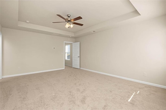 empty room featuring carpet, ceiling fan, and a tray ceiling